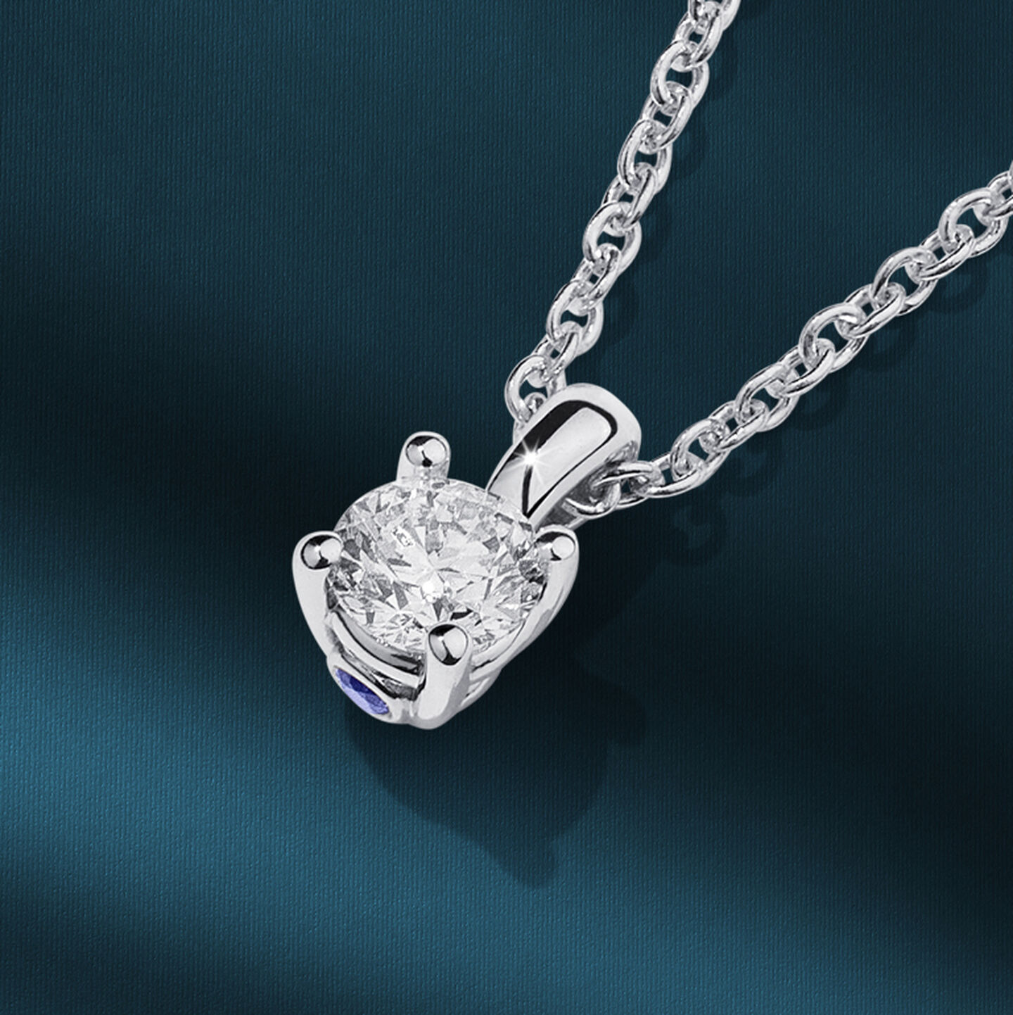 Pendentif avec diamant Birks Blue sur un fond bleu.
