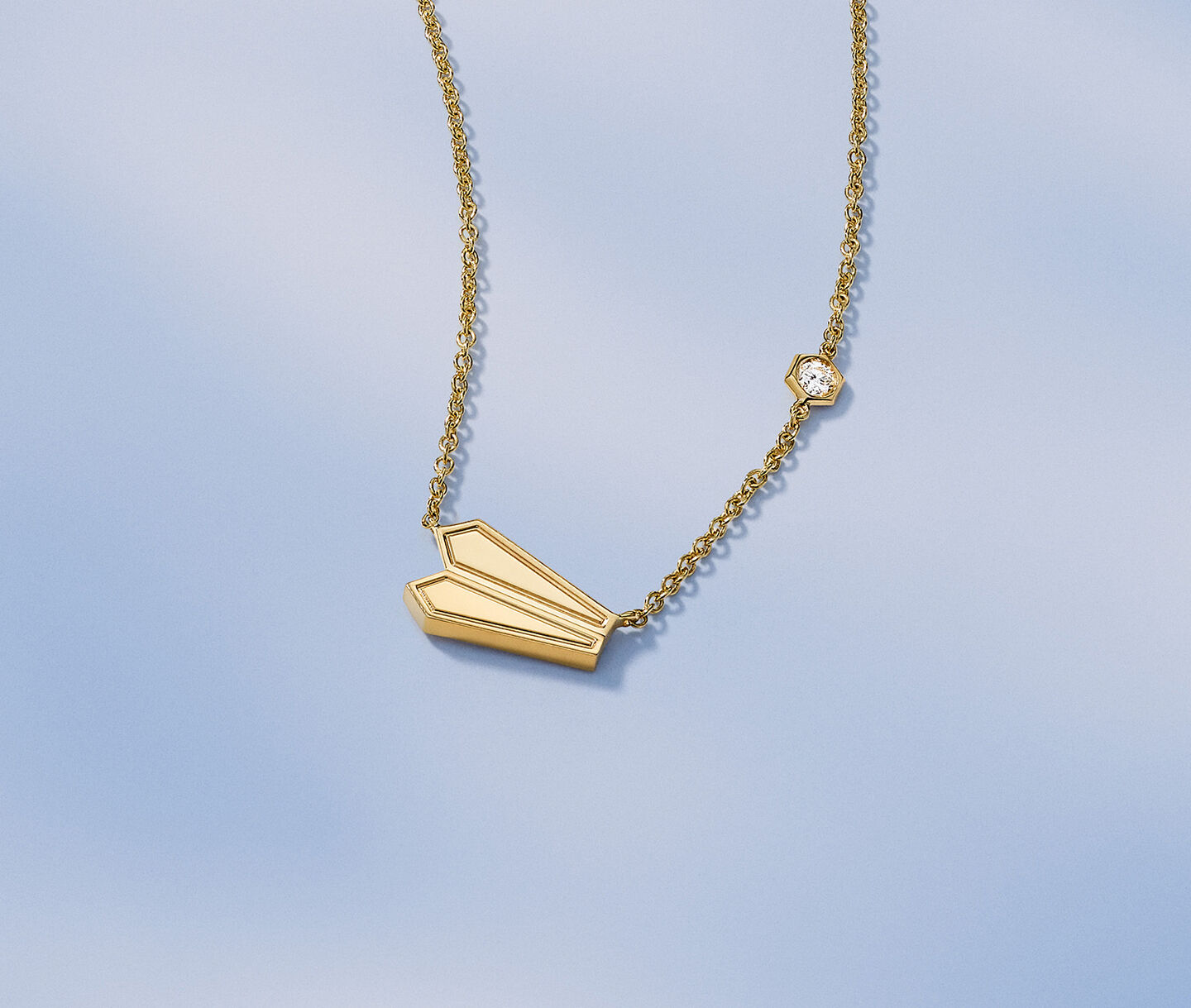 Birks Beekeeper yellow gold necklace on a blue background.