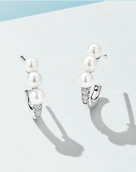 Boucles d'oreilles en perles et diamants de Yoko London ono sur fond bleu clair.
