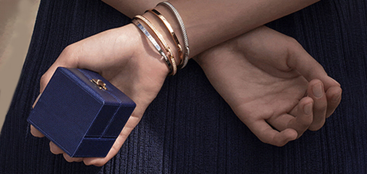 A model holds a Chaumet jewellery box wearing Chaumet gold bangles.