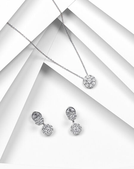 Birks Snowflake diamond earrings and pendant on a white layered background.