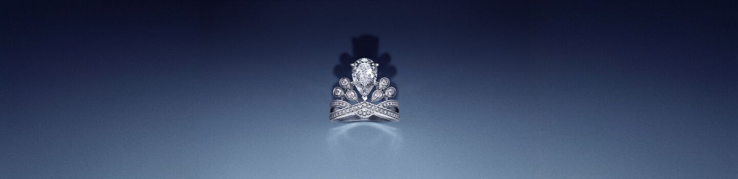 A Chaumet Jos&eacute;phine diamond engagement ring on a dark blue background.