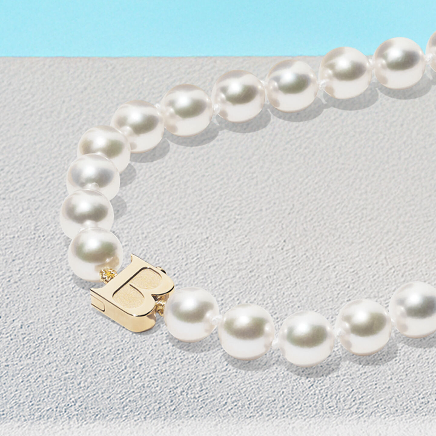 Birks Pearls necklace on a blue background.