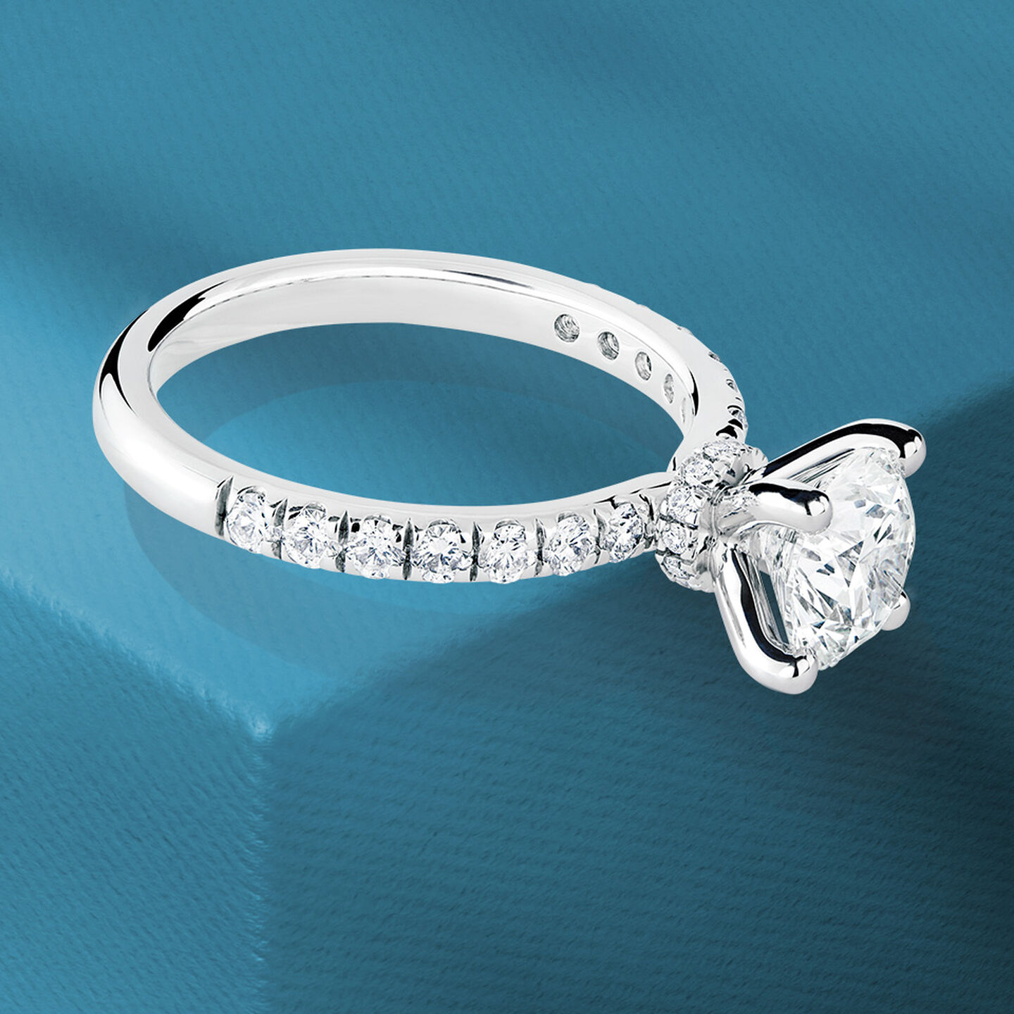 Birks Deco diamond engagement ring on a blue background.