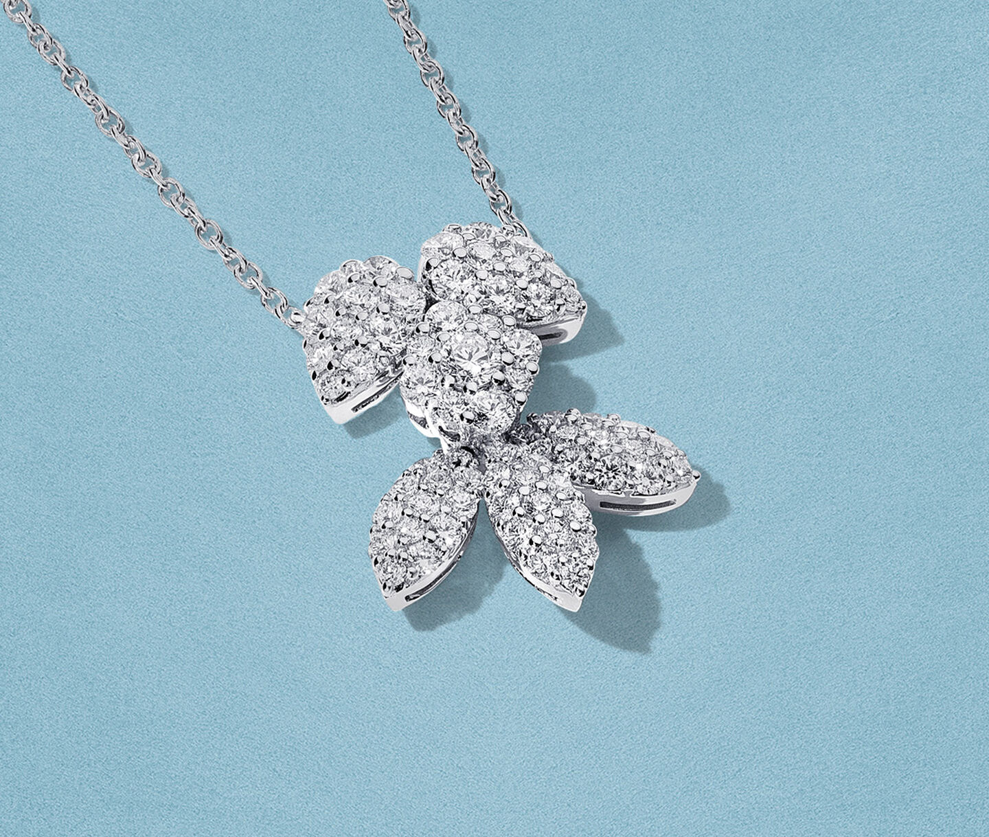 Birks Snowflake diamond necklace on a blue background.