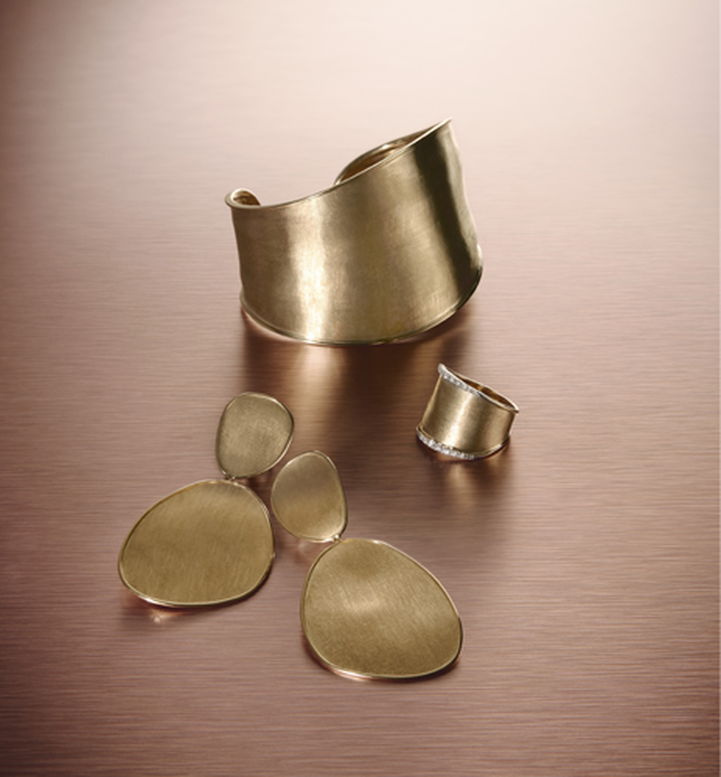 Bijoux Lunaria en or jaune de Marco Bicego sur un fond rose.