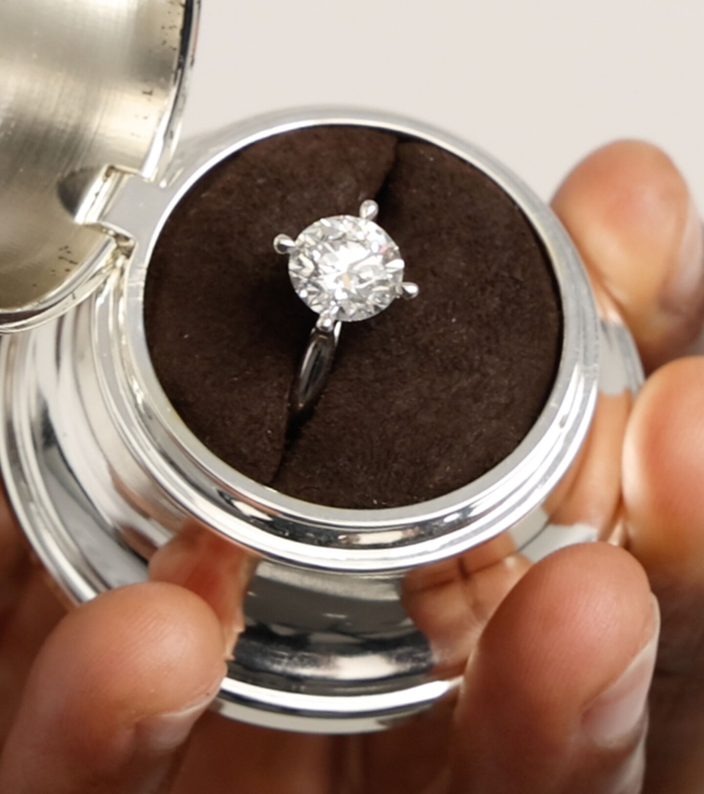 Someone holding a Birks engagement ring in a Birks Bell Box.