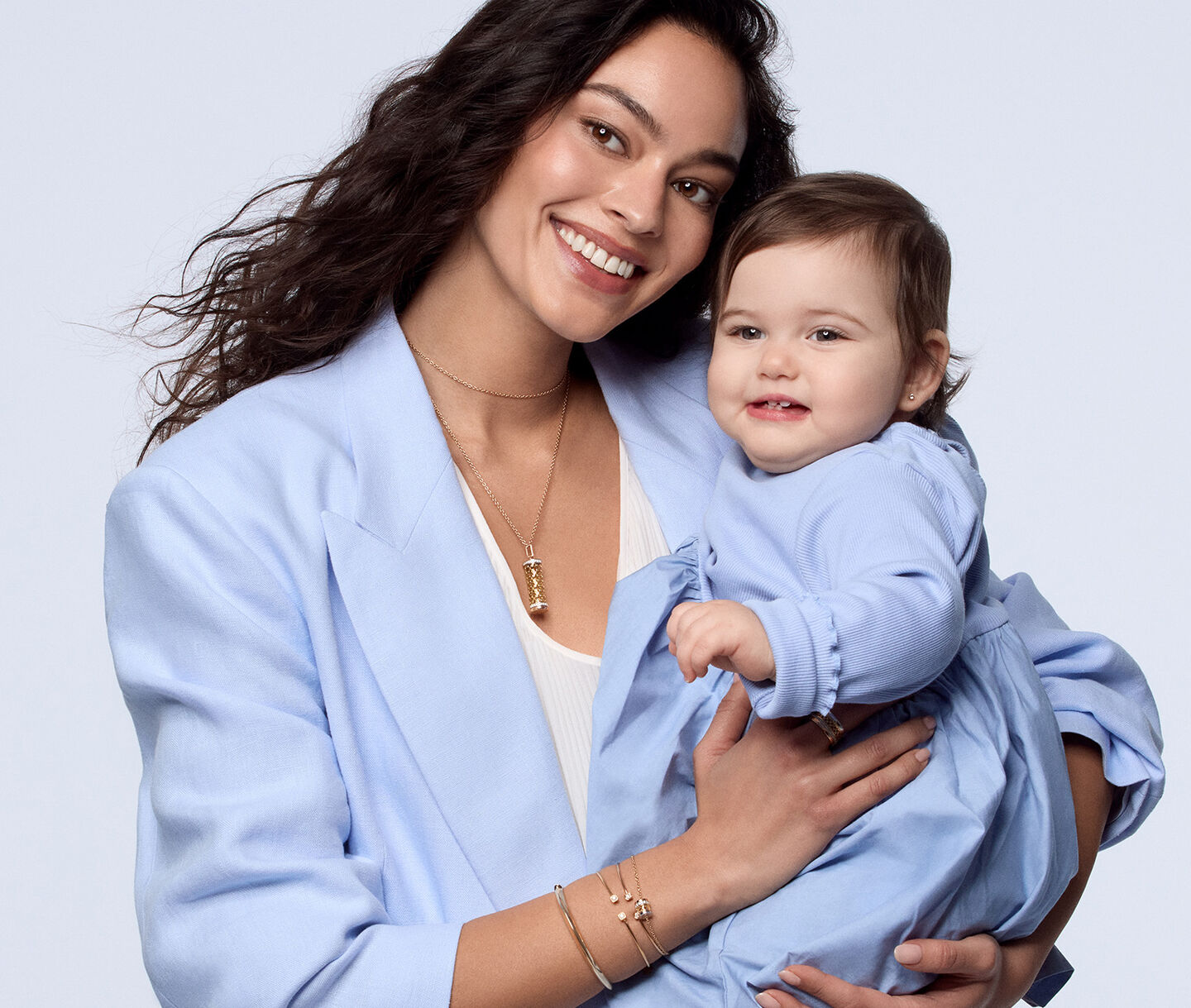 A woman holding a child wearing Maison Birks jewellery.