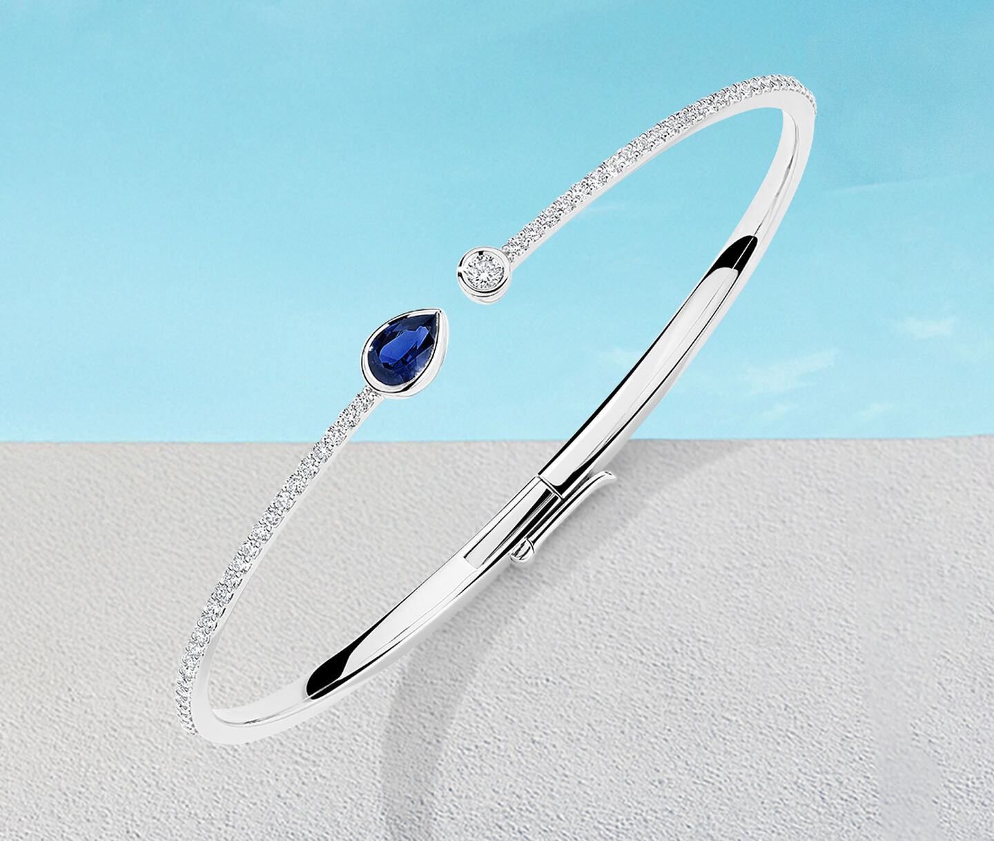 Birks Splash sapphire and diamond bangle bracelet on a blue background.