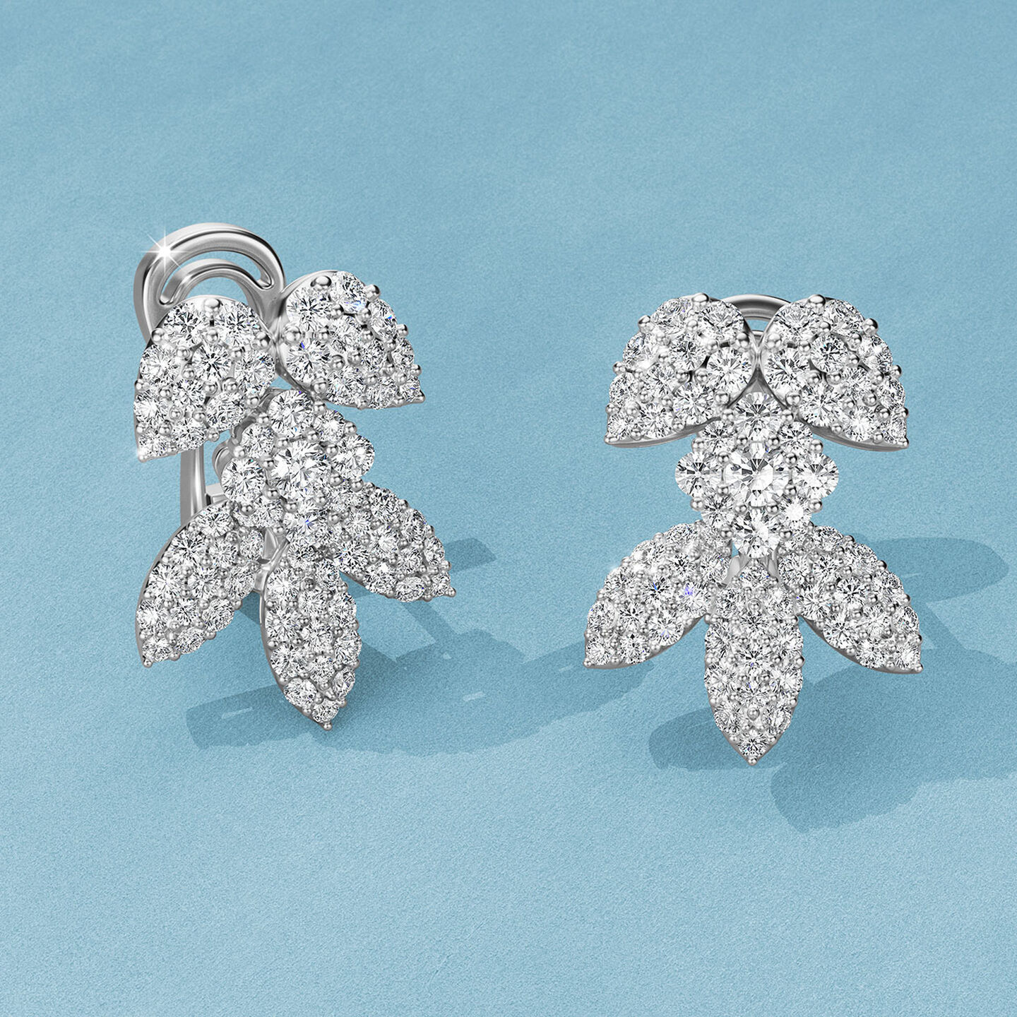 Boucles d'oreilles avec diamants Birks Snowflake sur un fond bleu.