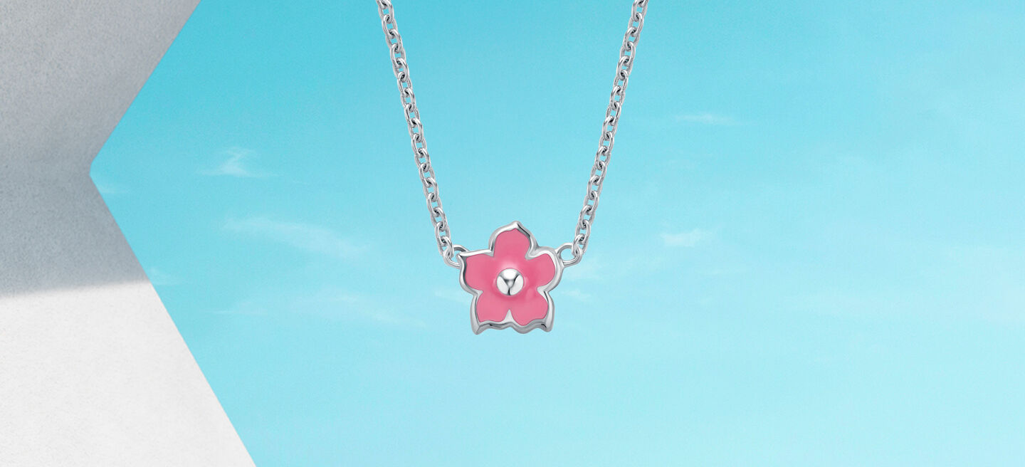 Birks enamel flower necklace on a blue background.