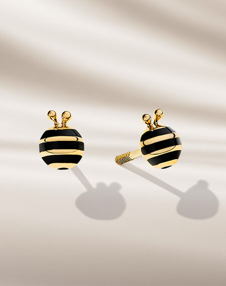 Boucles d'oreilles en or jaune pour enfants Birks sur un fond beige.