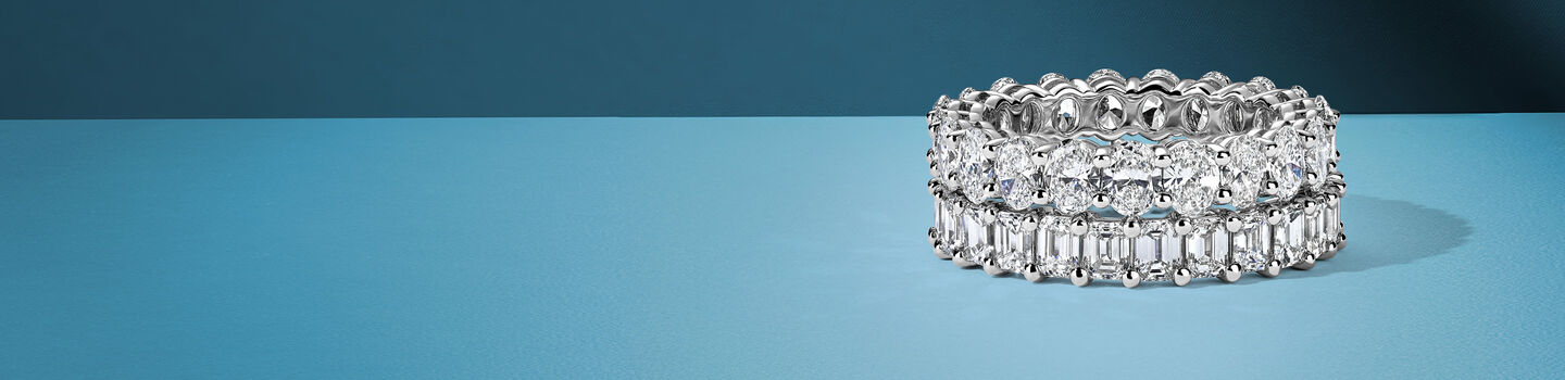 Oval and emerald eternity rings on a blue background.