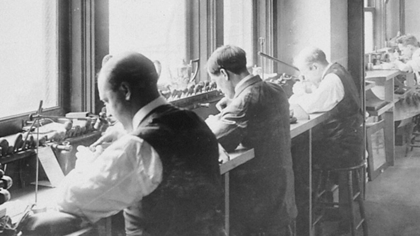 Black and white photo of Birks craftsmen working at a table.