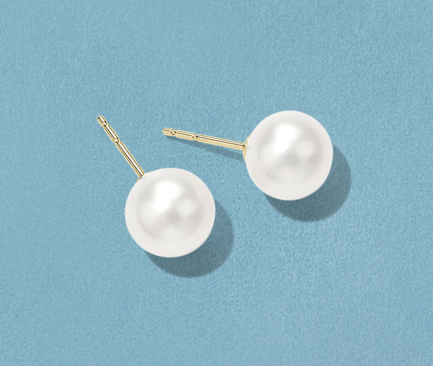 Birks Pearls earrings on a blue background.
