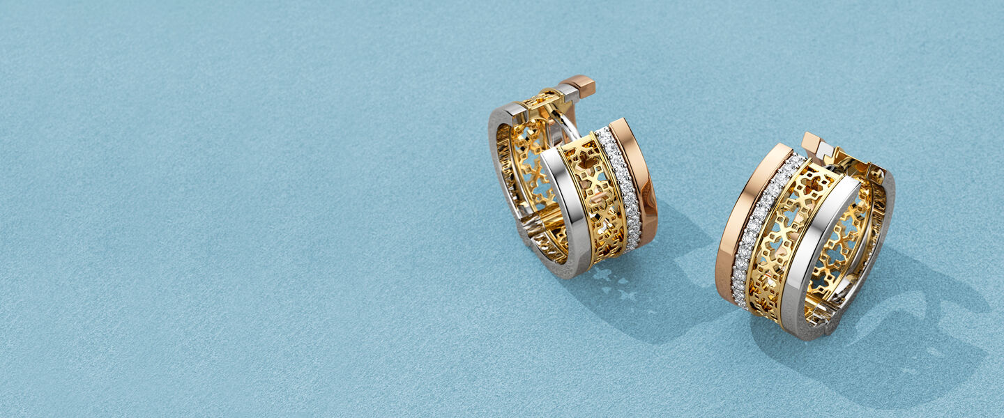 Boucles d'oreilles Birks Dare to Dream avec diamants sur un fond bleu.