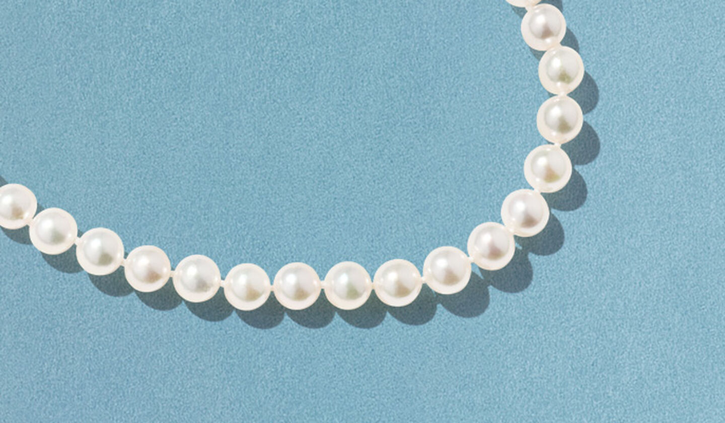 Birks Pearls necklace on a blue background.