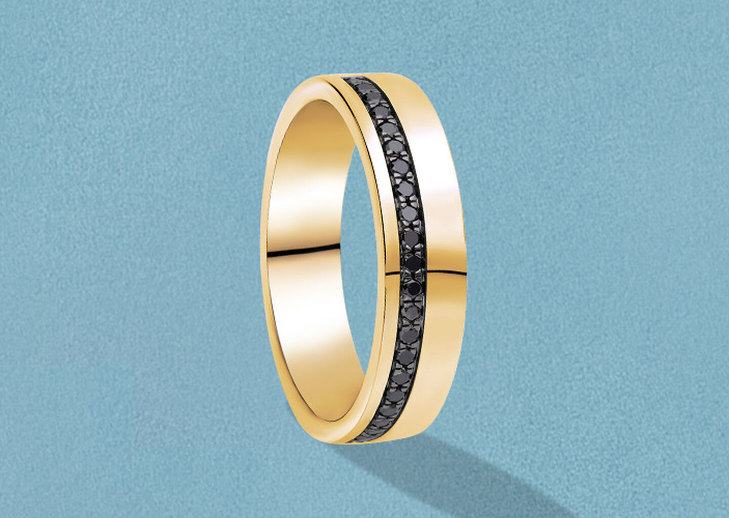 Birks men's gold and black diamond ring on a blue background.