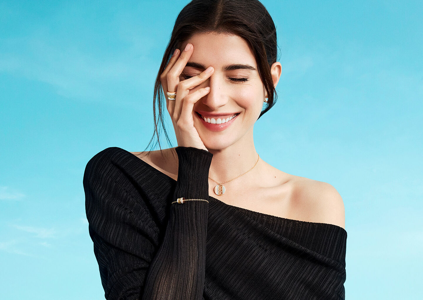 Une femme porte les bijoux Birks Dare to Dream sur un fond bleu.
