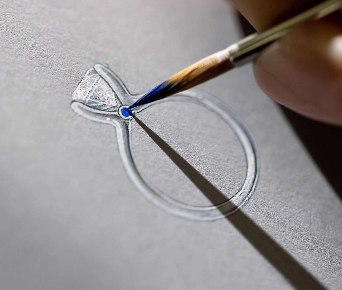 An artist painting a Birks Blue diamond engagement ring.