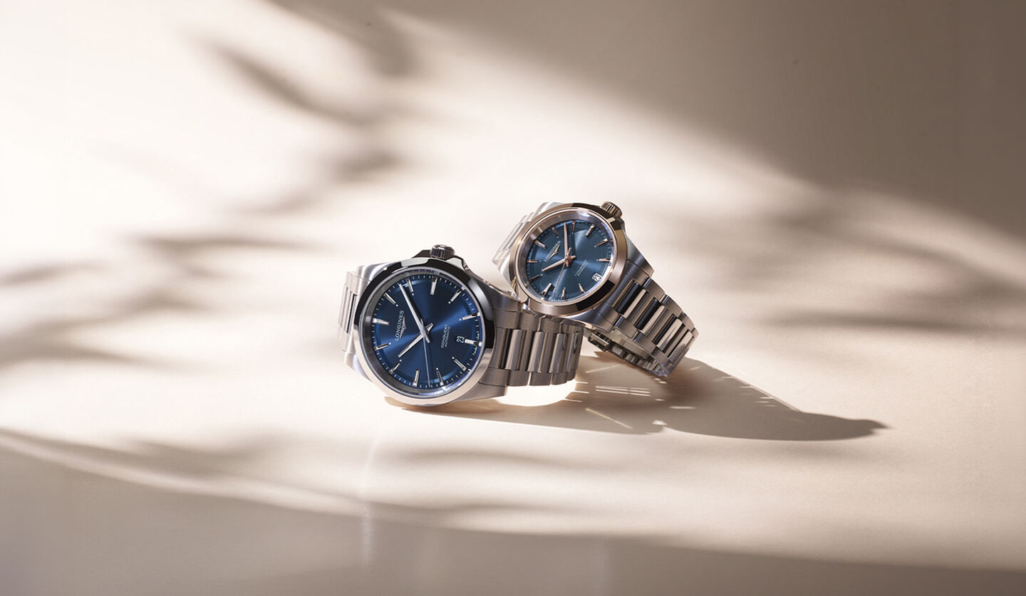 Two Longines watches on a beige background.