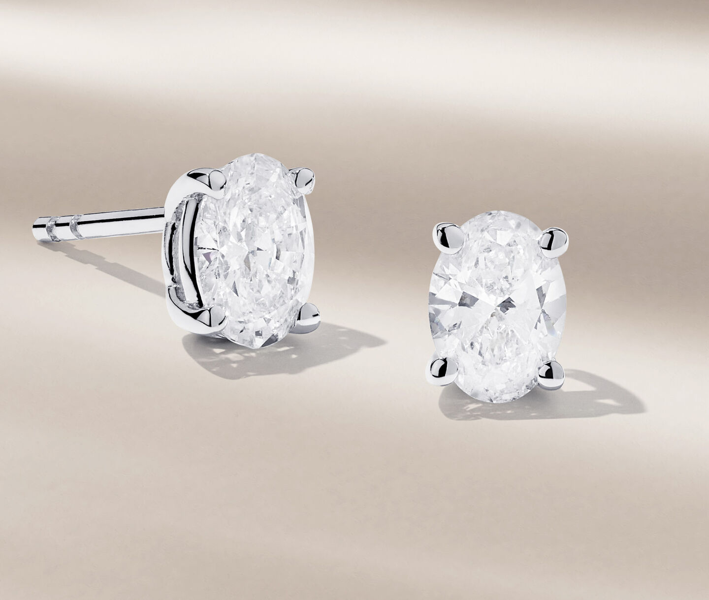 Birks Blue diamond stud earrings on a beige background.