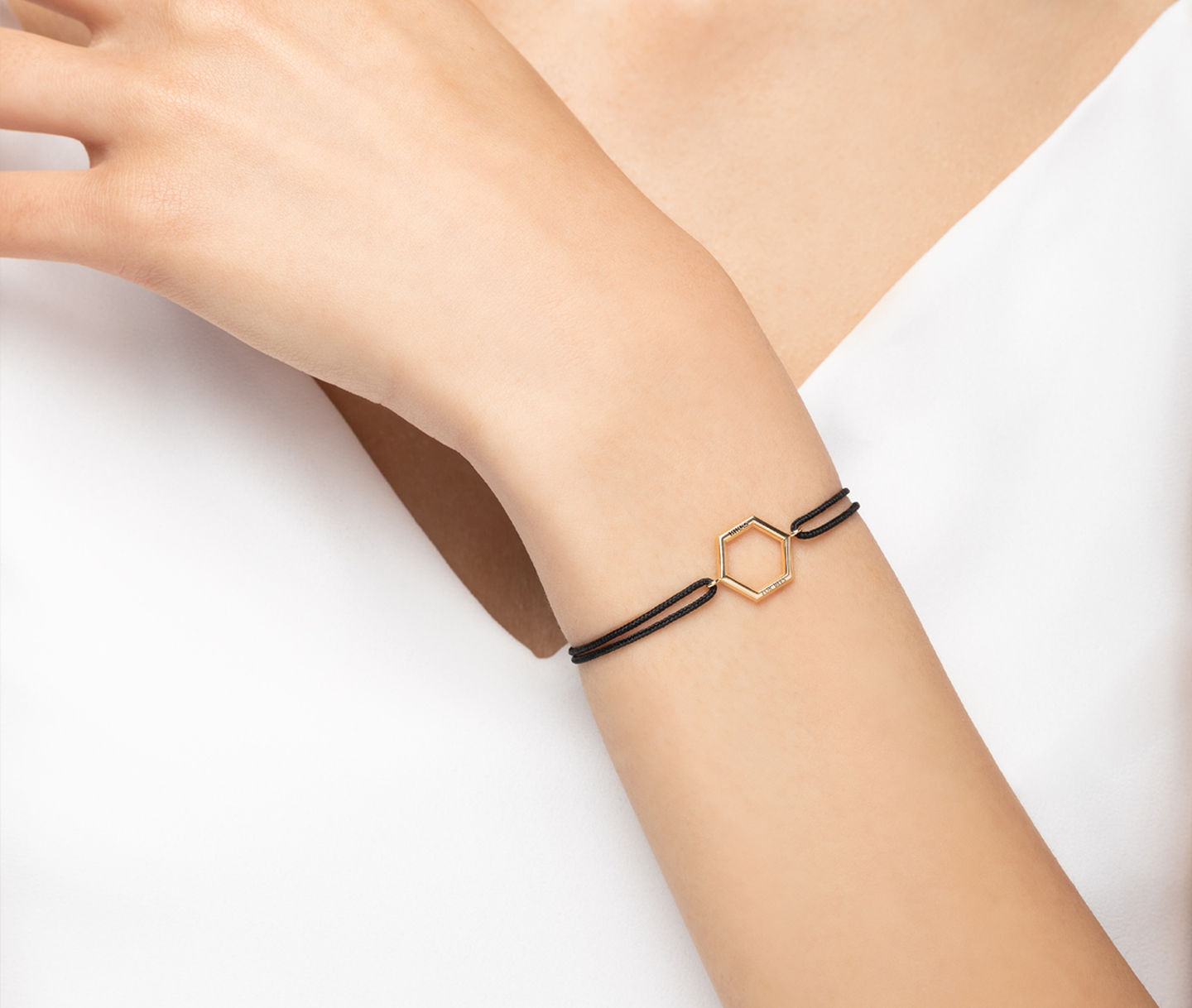 A woman wearing a Birks Bee Chic cord and gold bracelet.