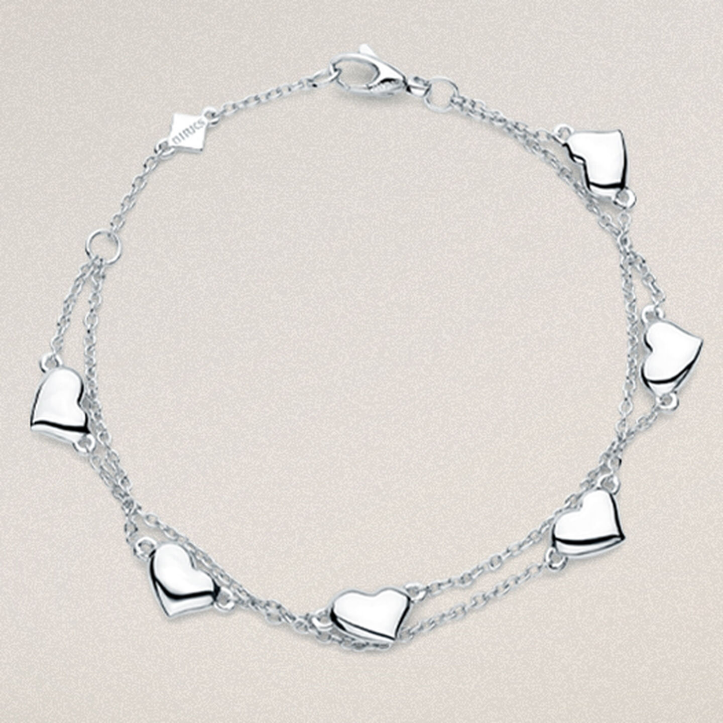 Birks heart bracelet in silver for babies on a beige background.
