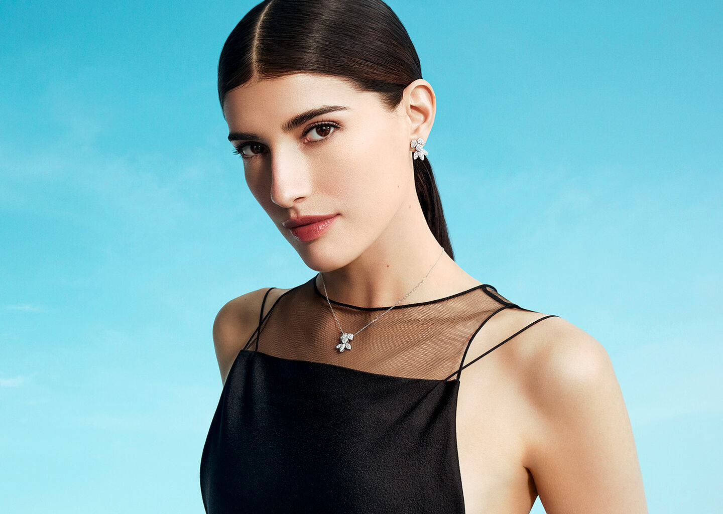 Une femme porte les bijoux Birks Snowflake sur un fond bleu.