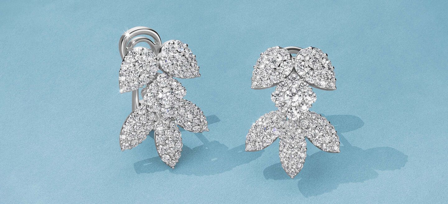Boucles d'oreilles Birks Snowflake avec diamants sur un fond bleu.