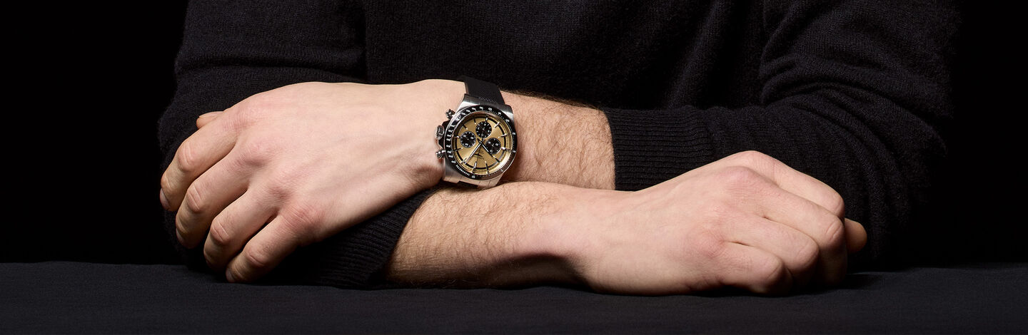 A closeup of a man's wrist wearing a Longines watch on a black background.