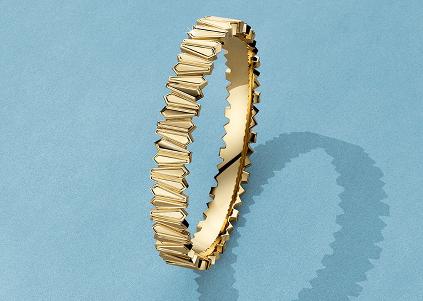 Birks Beekeeper yellow gold bangle on a blue background.