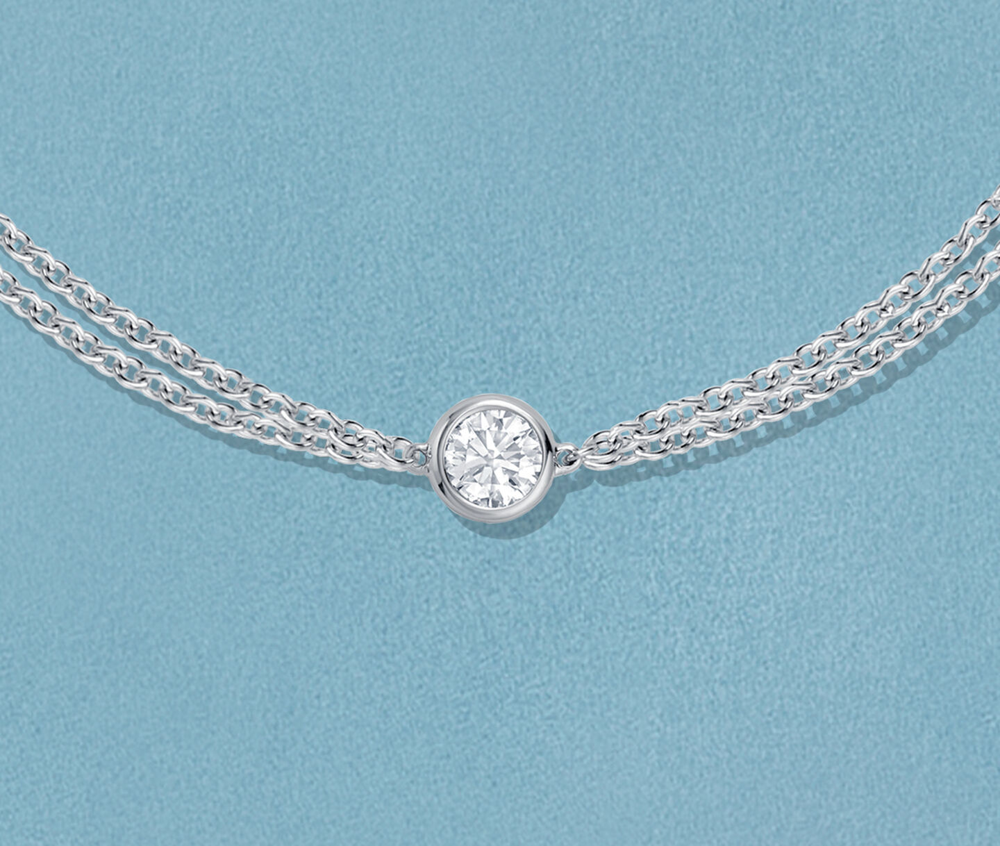 Bracelet Birks Essentiels en or blanc avec un diamants sur un fond bleu.