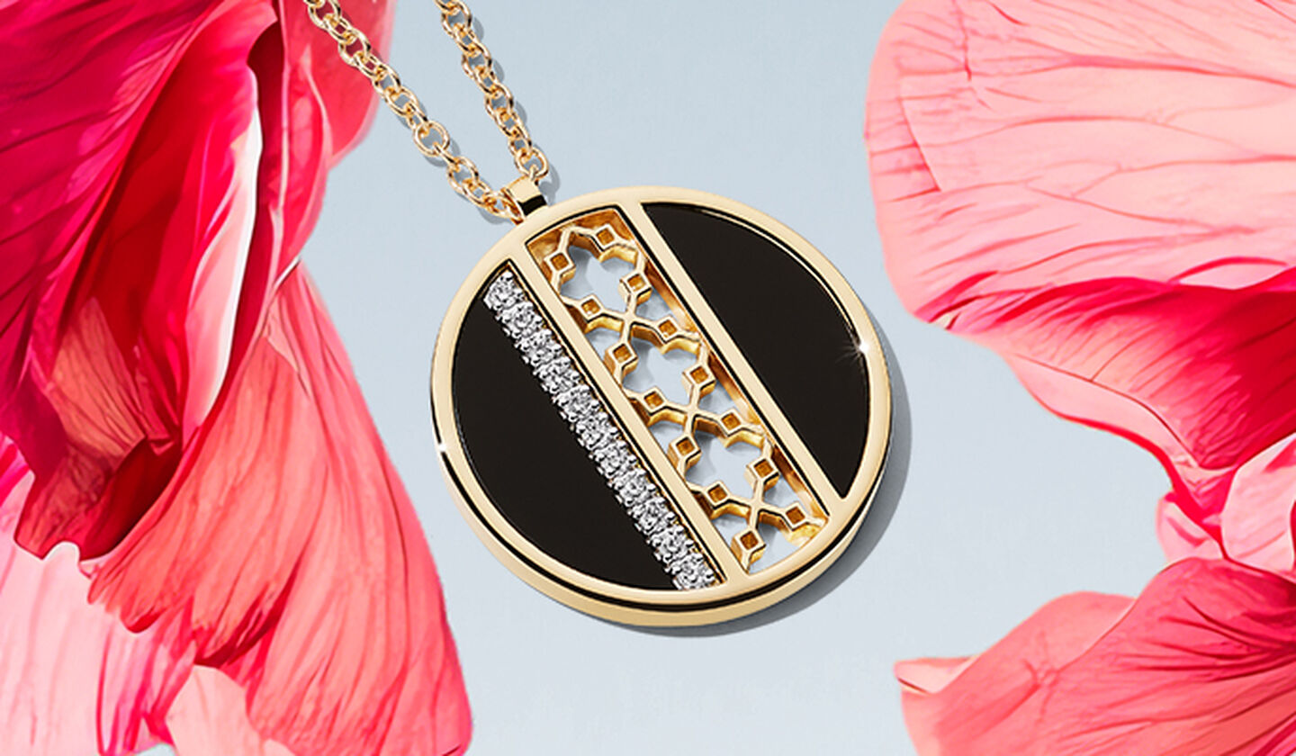 A Birks Dare to Dream onyx and diamond medallion on a pink flower light and sky blue background.