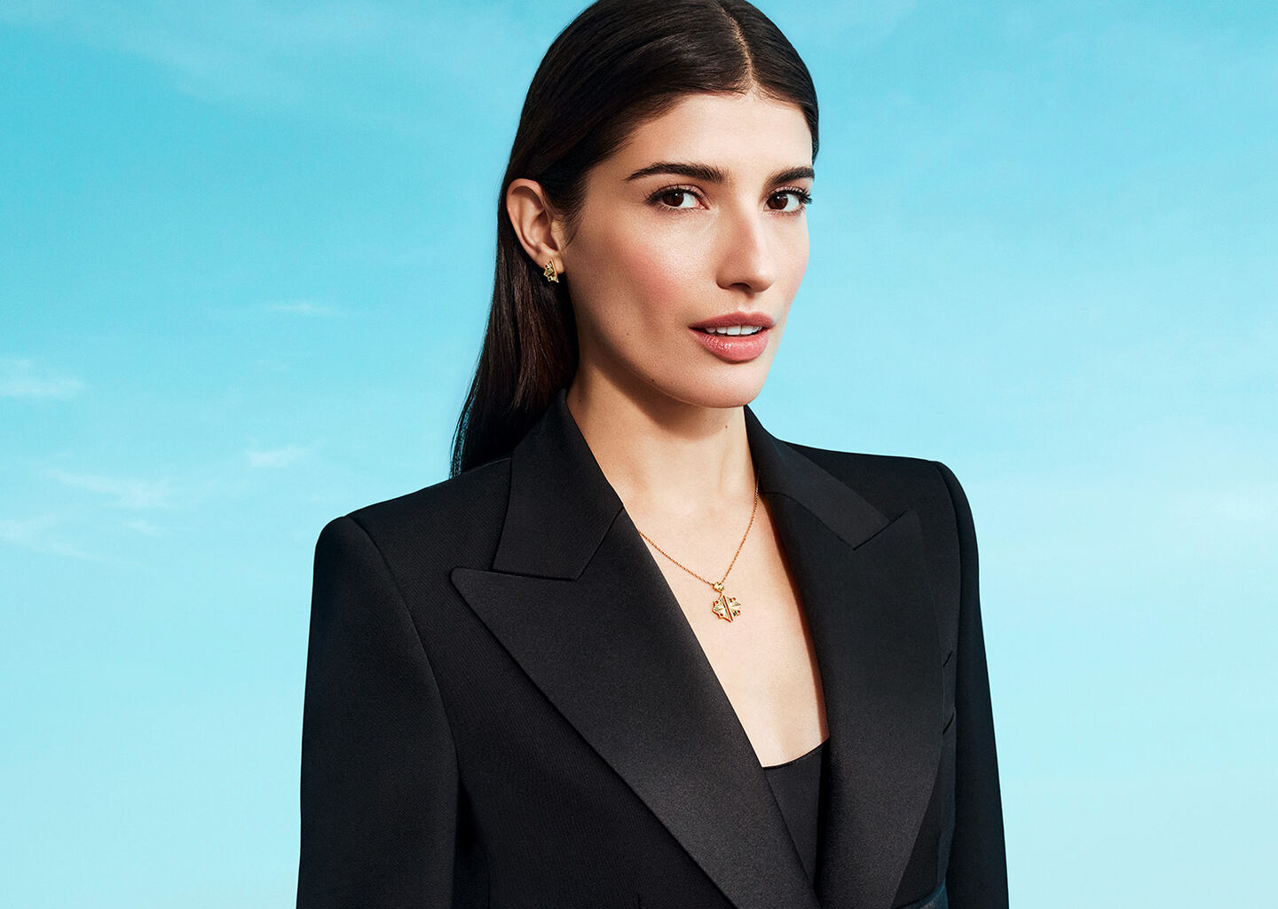 A woman wearing Birks Muse jewellery on a blue background.