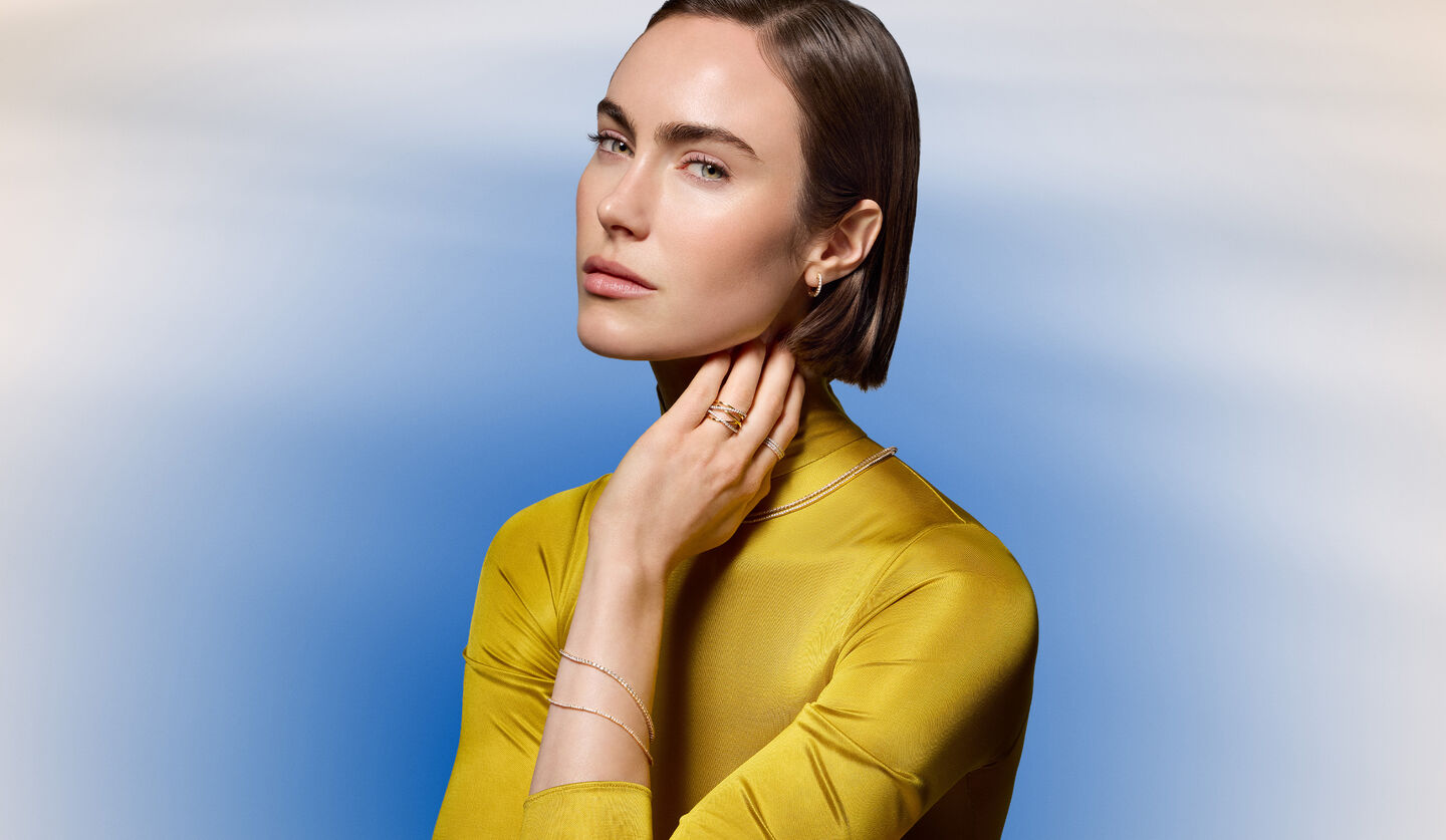 A woman wearing Birks diamond jewellery on a blue background.