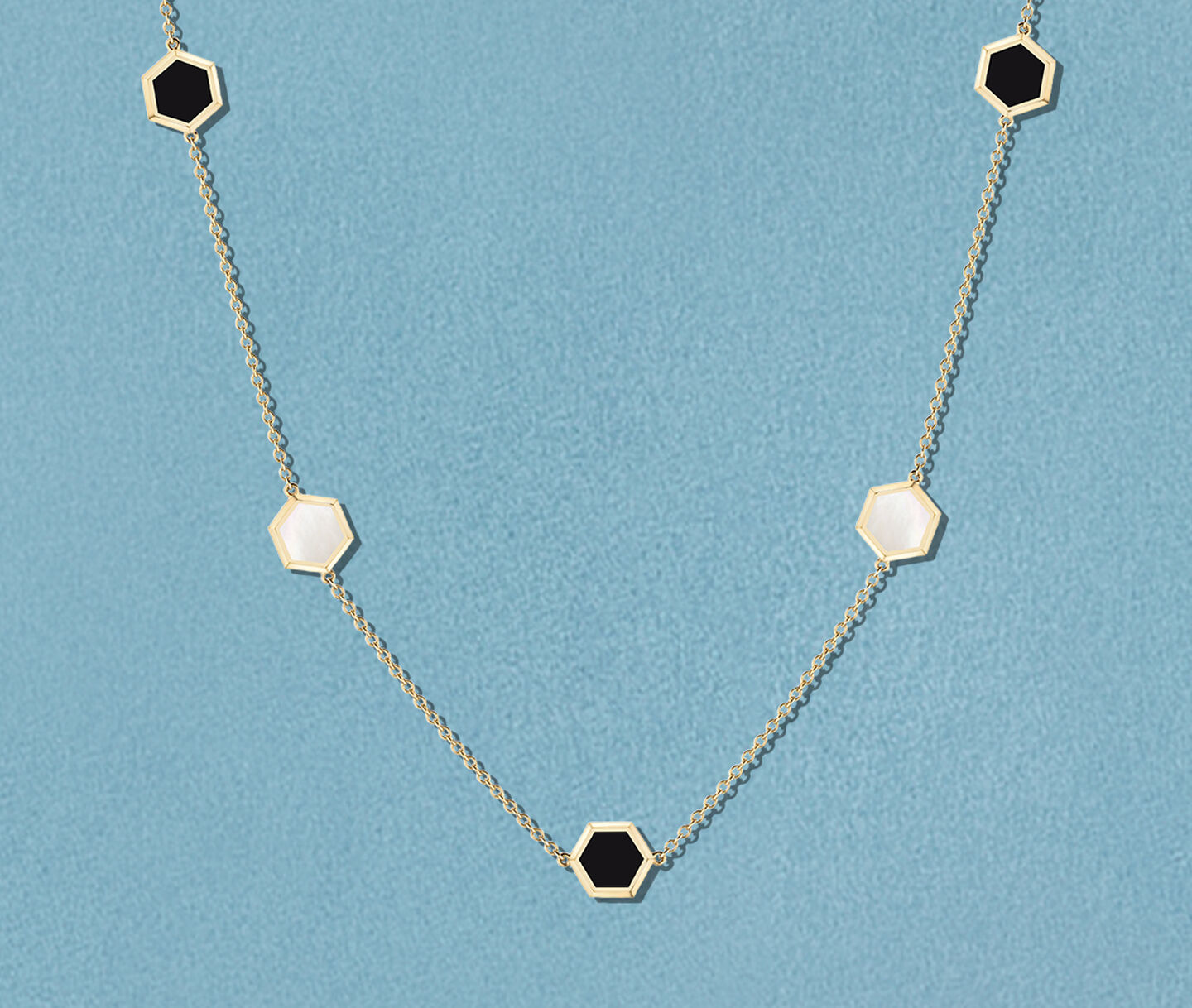 Birks Bee Chic onyx and mother-of-pearl station necklace. on a blue background