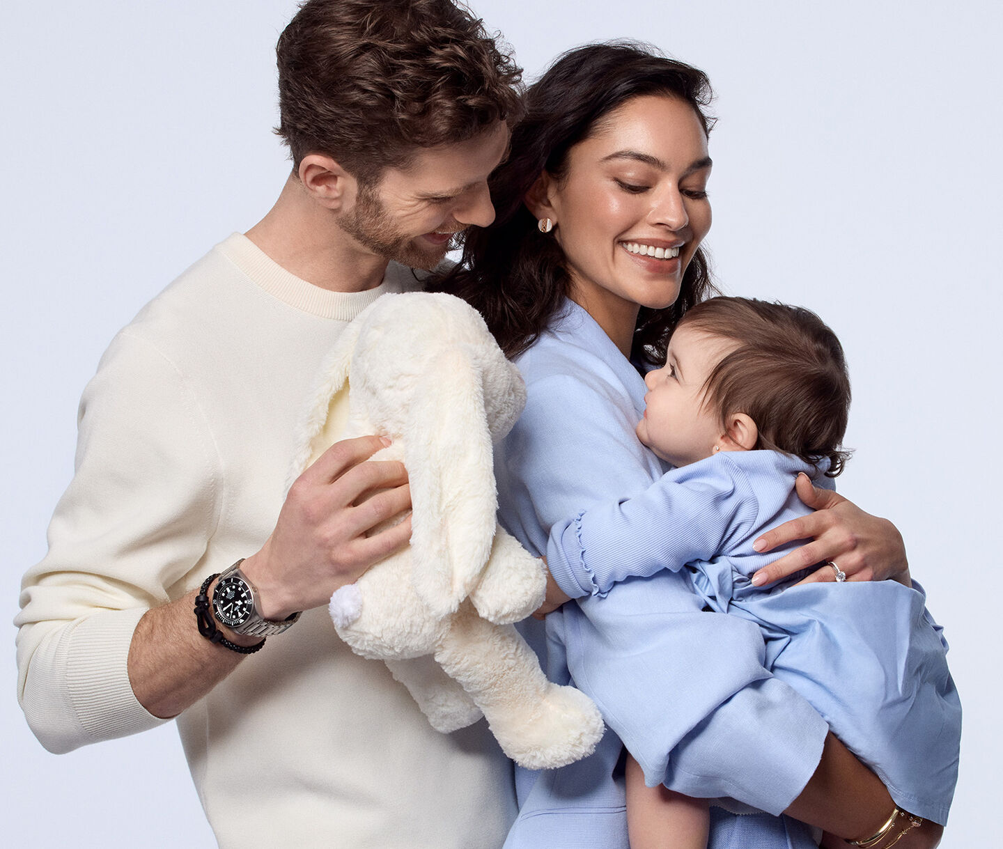 A man and woman holding a child wearing Maison Birks jewellery.