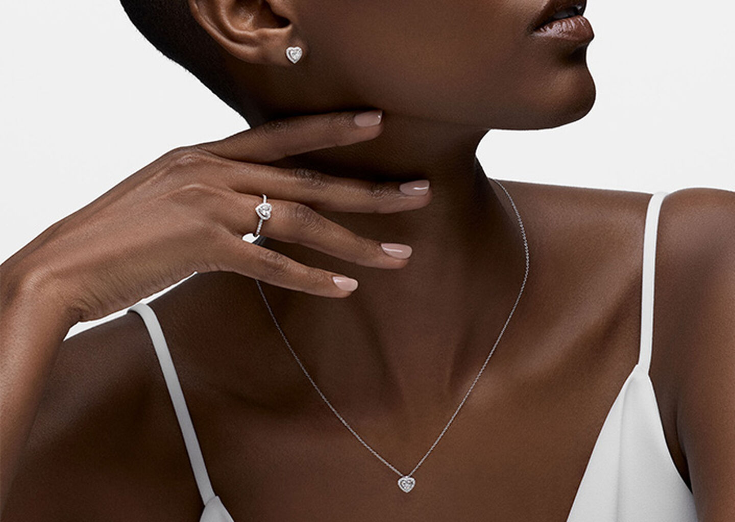 A woman wearing diamond heart-shaped Birks Essentials jewelry.