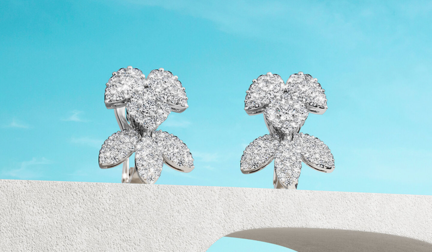 Boucles d'oreilles Birks Snowflake en or blanc et diamants sur fond bleu.