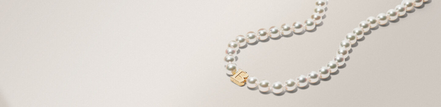 Colliers à perles Birks Pearls sur un fond tirant sur le gris et beige