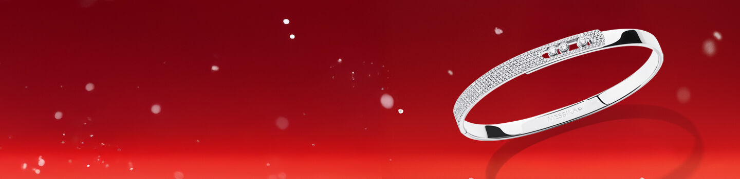 Messika Move Noa white gold and diamond bangle on a red holiday background.