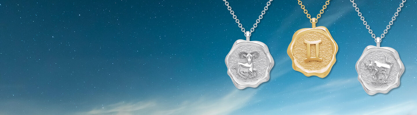 Pendentif Birks Essentiels Bélier, Gémeaux, et Taureau du zodiaque en or jaune et argent sur un fond étoilé.