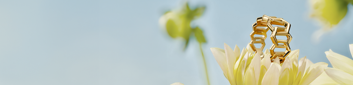 Bague en or jaune Birks Bee Chic sur une fleur blanche.