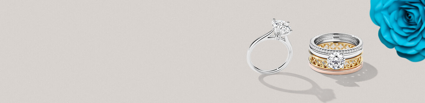Two engagement rings next to a blue rose