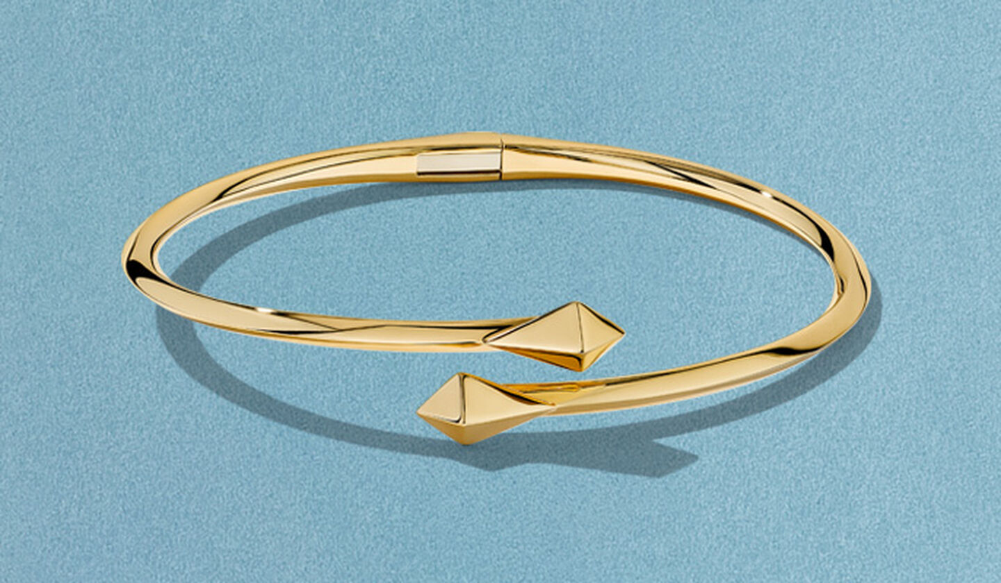 Birks Rock and Pearl gold bracelet on a blue background.
