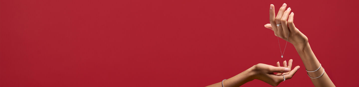 A woman holding Maison Birks jewellery on red background.