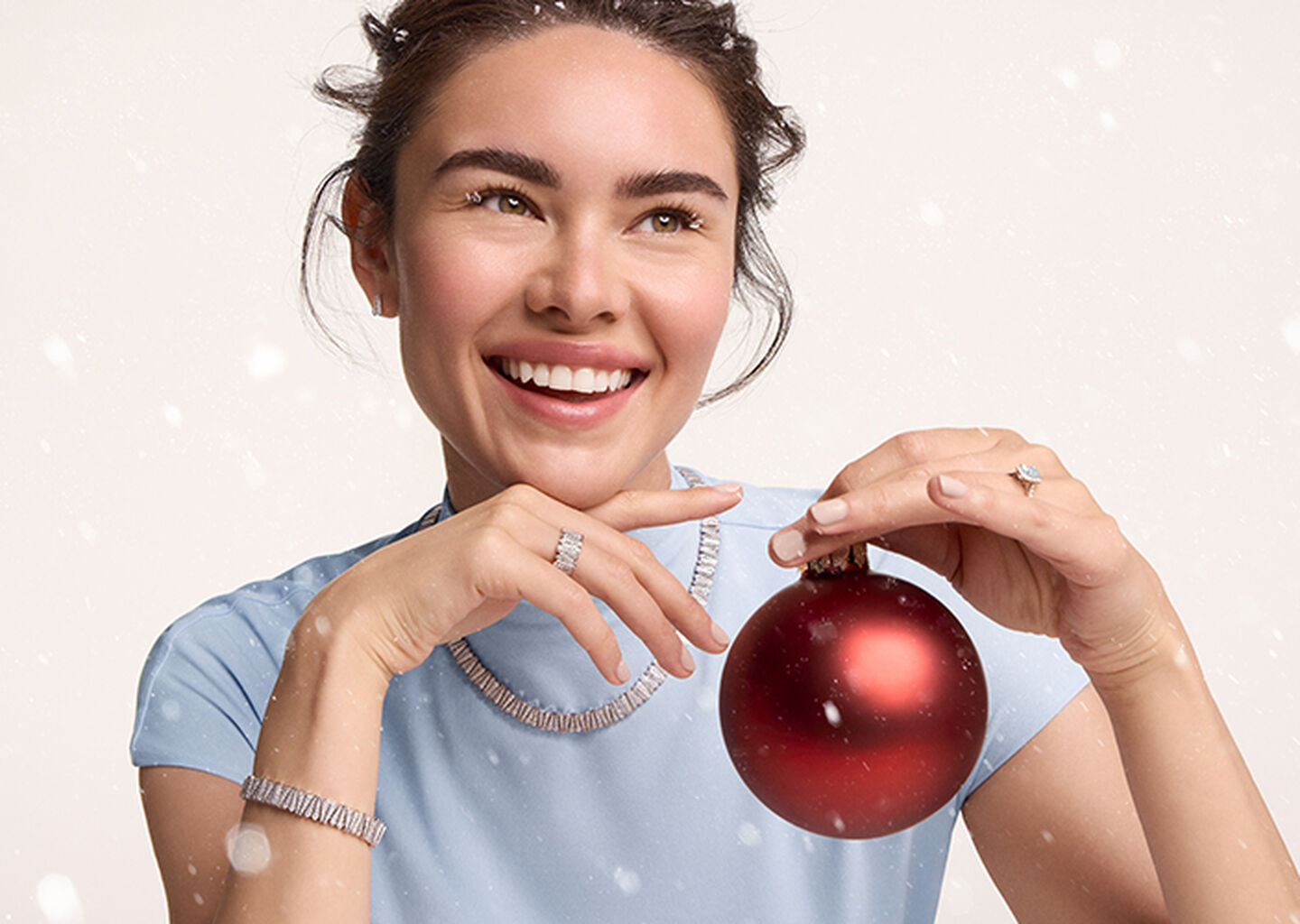 A person wearing Birks Beekeeper diamond jewellery collection on a beige snowy background.