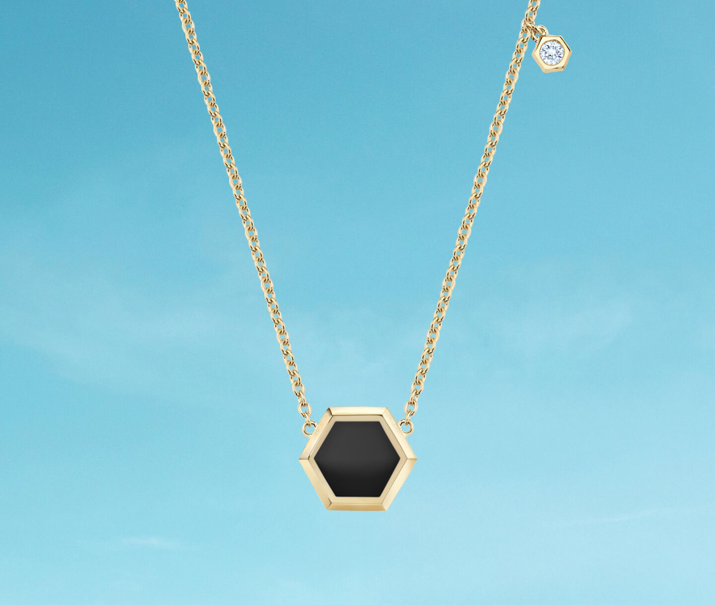 Birks Bee Chic onyx and gold necklace on a blue background.