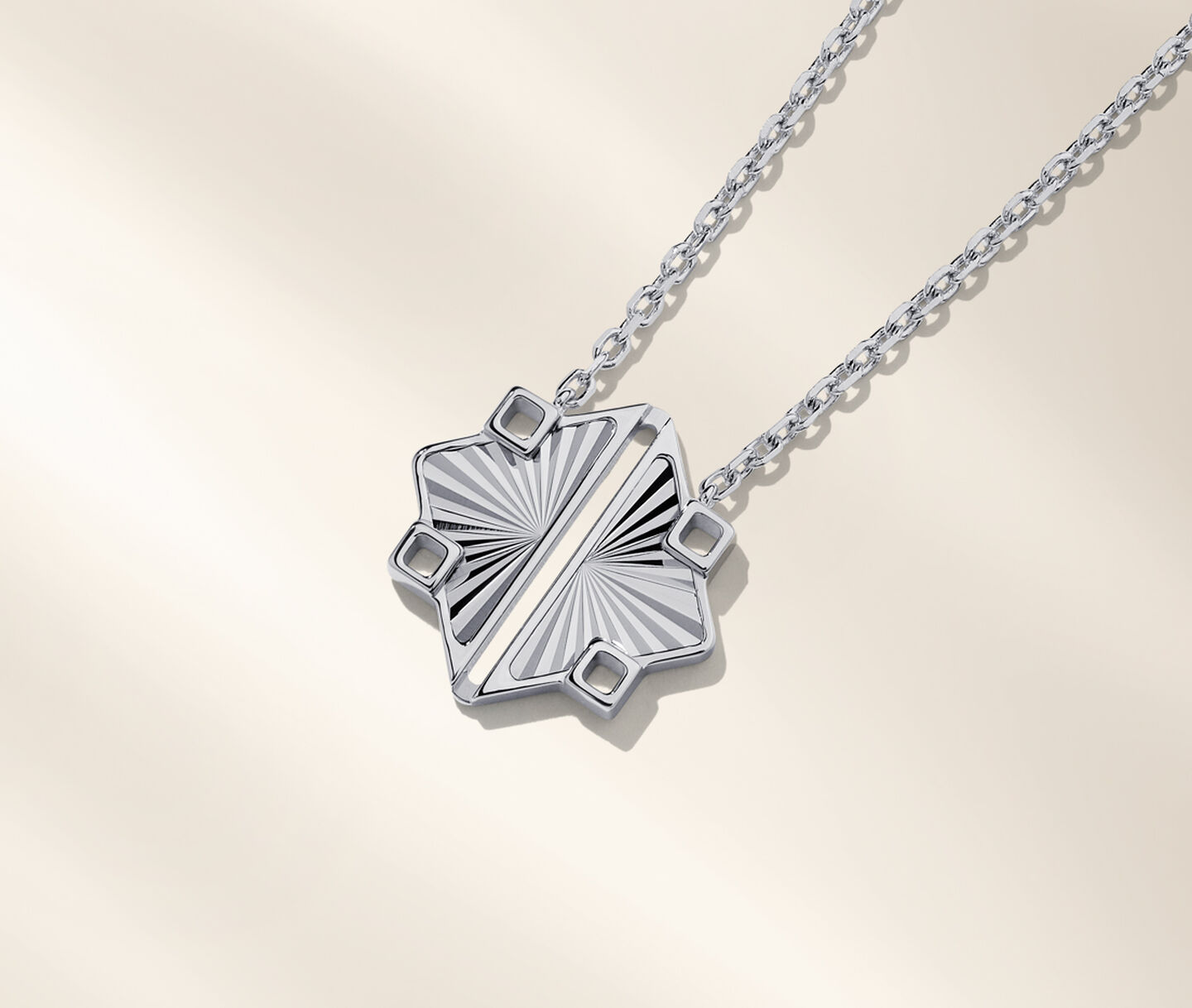 Birks Muse silver pendant on a beige background.